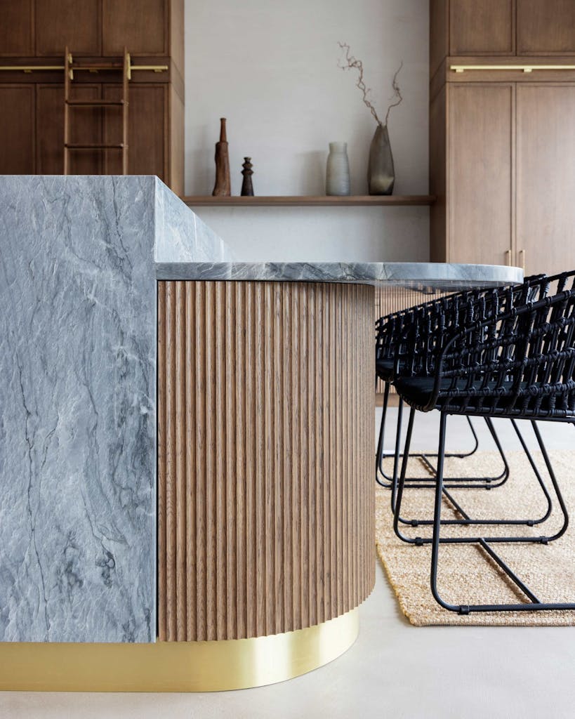 Bespoke modern kitchen in Esher with fluted oak cabinetry and leathered stone island by HUX London