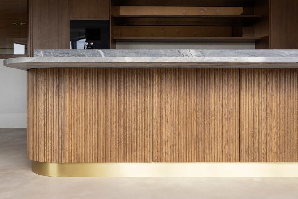 Bespoke modern kitchen in Esher with fluted oak cabinetry and leathered stone island by HUX London
